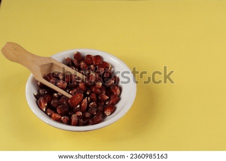 Mysuru, Karnataka, India-August 30 2023; A Close up picture of a few Red Corn or Maize seeds used as a food ingredient against a light yellow colored background.