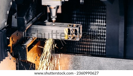 CNC industrial Automatic laser cutting machine for square metal profile, splashes of bright sparks. Concept modern industry background.