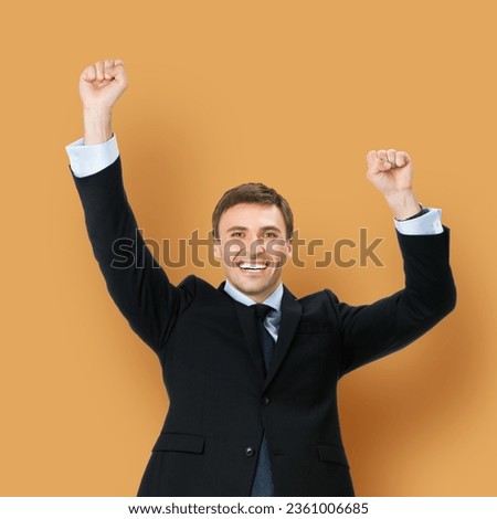 Square image of very happy, excited gesturing business man in black confident formal suit, necktie, raising hand fist, isolated brown beige color background. Advertisement ad concept photo Royalty-Free Stock Photo #2361006685