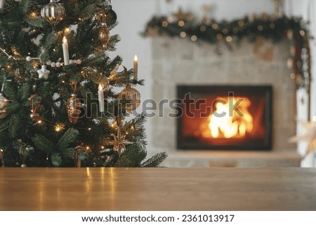Christmas festive template and wooden board mock up for product. Stylish wooden table against christmas tree with lights and burning fireplace. Christmas background, copy space