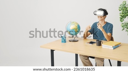Young student sitting at his desk and using VR goggles, virtual reality and education concept