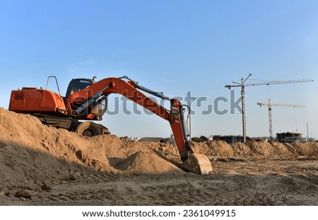 Excavator dig ground at construction site. Dig foundation. Tower crane on Construction of residential buildings. Earthmover Loader on groundwork. Excavator on earthmoving. Renovation project  Royalty-Free Stock Photo #2361049915