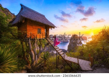Happy and relaxed travel woman watching sunrise, tree house with diamond beach, Atuh beach in Nusa Penida island, Bali, Indonesia. Royalty-Free Stock Photo #2361066635