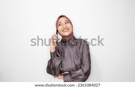Portrait of happy young muslim woman talking on mobile phone against white background