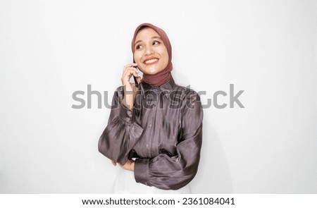 Portrait of happy young muslim woman talking on mobile phone against white background
