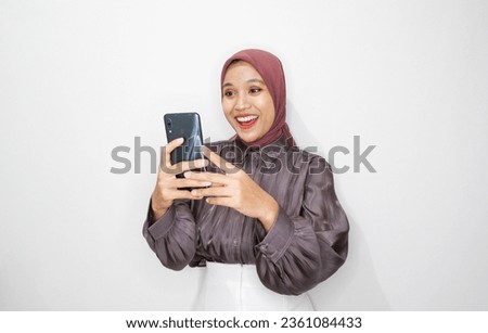 Portrait of young Asian muslim woman using mobile phone against white background