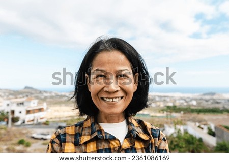 Happy Thai woman having fun having fun smiling into the camera at house rooftop Royalty-Free Stock Photo #2361086169