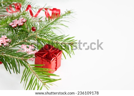Closeup of pine branch, snow flakes,  red colored Christmas decoration box on white background with copy space