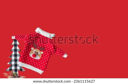 Christmas New Year background. Christmas tree figurine in checkered colors and christmas sweater on a red background. Lots of free space for your ideas and texts.
