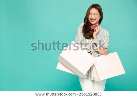 Young beautiful Asian woman holding paper shopping bag and showing credit card isolated on green background, Supermarket and fashion mall concept Royalty-Free Stock Photo #2361128835