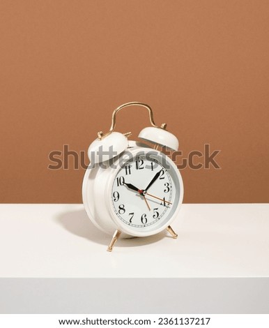 Analog white retro alarm clock on brown background. Idea of deadline and hard work.