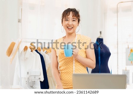 portrait of young fashion stylist designer happy smiling with coffee cup, dressmaker design clothing for her new collection, female freelance tailor working at home dress shop small business owner