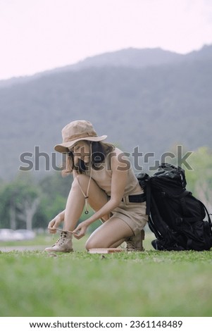 Young Asian woman traveler sitting with backpack at natural park, Activity and lifestyle on holiday, eco-friendly adventures, Happy woman forest or park backpack concept.
