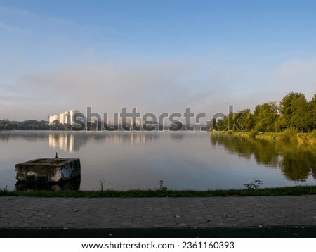 Ivano-Frankivsk lake with the morning fog. Water from the lake evaporates under the influence of morning sunlight. Beautiful water landscape. Cozy atmosphere of peace and tranquility.