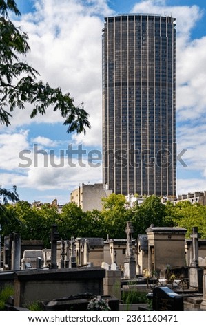 Breathtaking vista of Montparnasse Tower against a serene backdrop of Montparnasse Cemetery in Paris, France.
