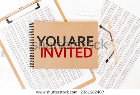 Craft colour notepad with text YOU ARE INVITED. Notepad with eyeglasses and text documents. Business concept