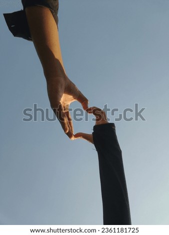 A couple in love takes a photo of their hands forming a love symbol which suggests that love is truly amazing. 2 hands that bind each other are faithful forever 