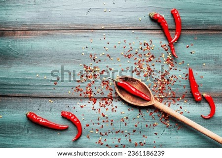 Red hot spicy cayenne peppers, both fresh and dried seeds, in wooden spoon. Flat lay over rustic background.