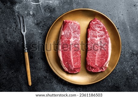 Raw Shoulder Top Blade beef meat steaks on a plate. Black background. Top View. Royalty-Free Stock Photo #2361186503