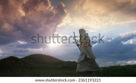 Jesus Christ silhouette walking on a hill shrouded in twilight. Royalty-Free Stock Photo #2361193221