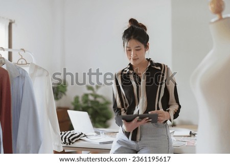 Asian Woman Fashion Designer Stylish Artist or creative designer drawing on sketch book with new project design working in studio
