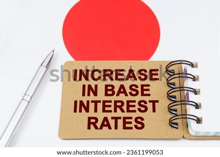 Economy and finance concept. On the flag of Japan lies a pen and a notebook with the inscription - increase in base interest rates.