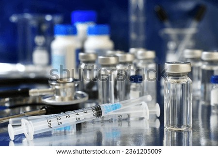 Vaccine booster tripledemic concept background - vials of generic vaccines with syringe and stethoscope Royalty-Free Stock Photo #2361205009