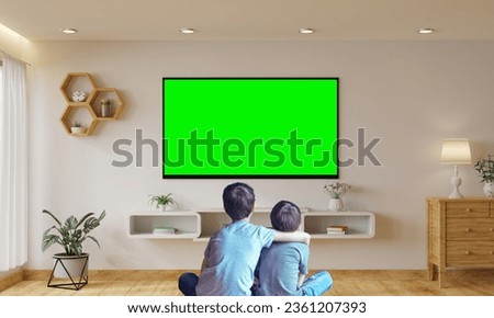 Asian Little kid watching green-screen TV Alone in the living room, surrounded by a lot of toys. selective focus, white shirt kids watch media. Back-view.
