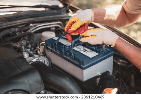 auto mechanic repairs a car. A mechanic removes a car battery from the box. Royalty-Free Stock Photo #2361210469