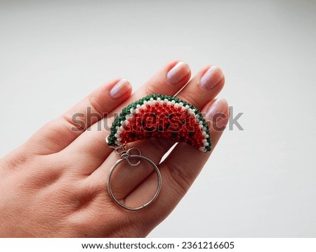 Red fruit keychain lies on a woman's palm. Watermelon keychain lies in hand
