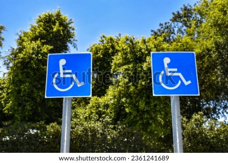 two disabled parking signs against a blue sky