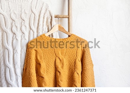 Warm autumn sweaters on hangers. Comfort knitwear for cold days of fall, winter. Fashion, thifting, sustainable second hand shopping idea