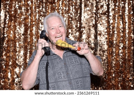 Photo Booth. Chicken Leg Phone. A man talks in his Chicken Leg Telephone while having his pictures taken in a Photo Booth at a Party. Chicken Leg Telephones are the latest technology. Photo Booth Fun.