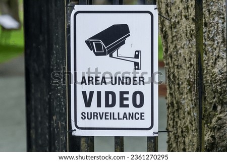 Area Under Video Surveillance Warning sign with picture illustration of camera mount on the wall, black writing on white background