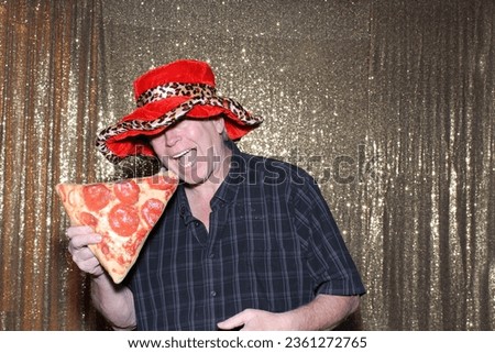 Photo Booth. FOOD. A man smiles and enjoys a Pizza while having his picture taken in a Photo Booth at a Wedding or Party. People love Photo Booth almost as much as their Lunch or Dinner. Snacks. 