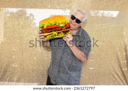 Photo Booth. FOOD. A man smiles and enjoys a Hamburger while having his picture taken in a Photo Booth at a Wedding or Party. People love Photo Booth almost as much as their Lunch or Dinner. Snacks. 