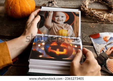 Halloween printed photos in photo album. Hands browsing picture album.