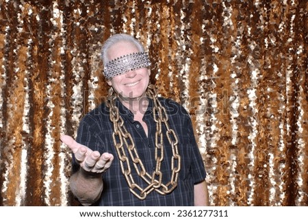 Photo Booth. Gold Chains. A man smiles and poses with his Gold Chains while having his pictures taken in a Photo Booth. Everyone loves a Photo Booth at Parties and Events. Even men in chains.