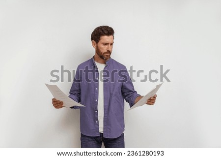 Focused entrepreneur or salesman holding financial documents and looking on it on white background