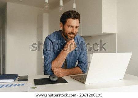Male entrepreneur working on laptop on home kitchen. Distance work concept. High quality photo