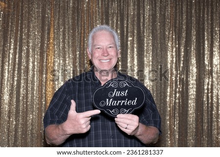 Photo Booth. A smiles as he holds a Just Married sign while having his pictures taken in a Photo Booth. Just Married Sign.  Photo Booth Sign. Wedding Photo Booth.  Will work for WEDDING CAKE. Love.