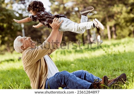 Grandfather having fun with his grandson in a park Royalty-Free Stock Photo #2361284897