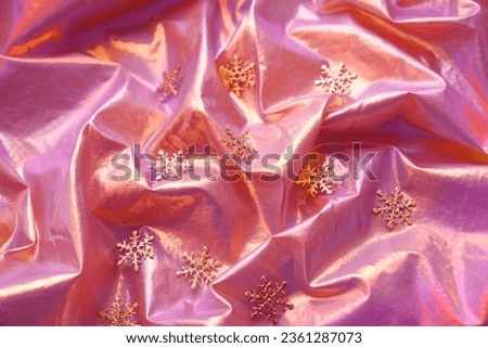 Luxury Christmas background with golden decorations snowflakes, iridescent wavy fabric background, neon coloring, pink, golden, purple. Full Frame