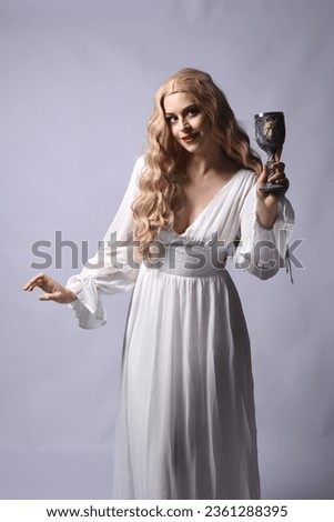 Close up portrait of beautiful blonde model wearing elegant  white halloween gown, a historical fantasy character.  Holding wine goblet, isolated on audio background.