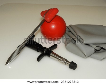 Chiropractic adjustment tool with a red reflex hammer, a gray elastic, and a red stress ball Royalty-Free Stock Photo #2361293613