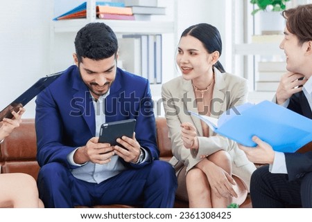 Asian young professional successful professional, business man and business woman in formal suit holding tablet computer, document folder, sitting and speaking chatting deal the business at lounge
