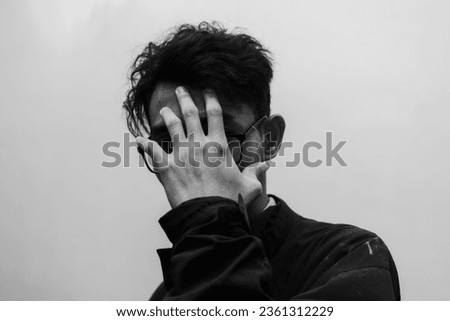 a person with curly hair and glasses covering his face, black and white photo