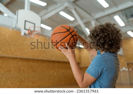  A medium shot of a determined kid holding a basketball, ready to take on the court with boundless enthusiasm.