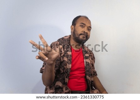 Handsome man wearing batik outer and red t-shirt inner posing on isolated background
