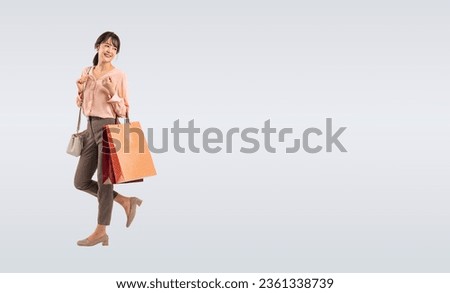 Asian middle-aged woman walking cheerfully with shopping bags Royalty-Free Stock Photo #2361338739